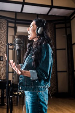 kayıt stüdyosunda mikrofonyakınında şarkı söyleyen çekici duygusal kadın