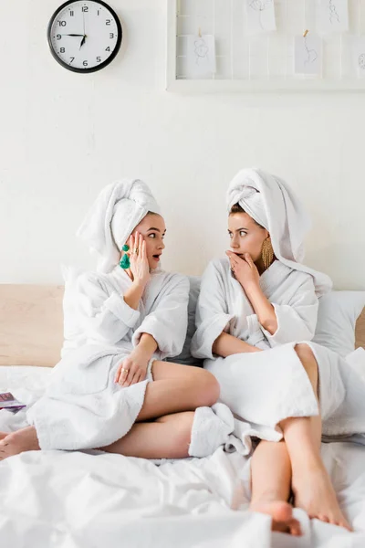 Geschokt Stijlvolle Meisjes Oorbellen Badjassen Met Handdoeken Hoofden Zittend Bed — Stockfoto