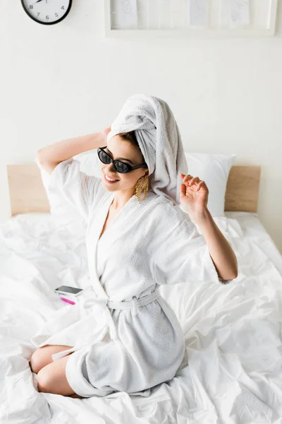 Счастливая Стильная Женщина Халате Солнцезащитных Очках Полотенце Украшения Сидя Постели — стоковое фото