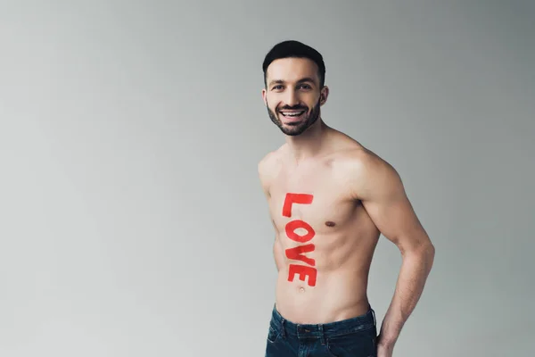 Laughing man in jeans with inscription on body on grey