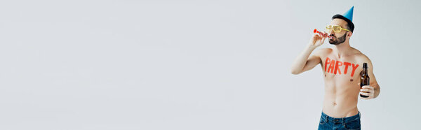 panoramic shot of shirtless man with party blower holding bottle of beer isolated on grey