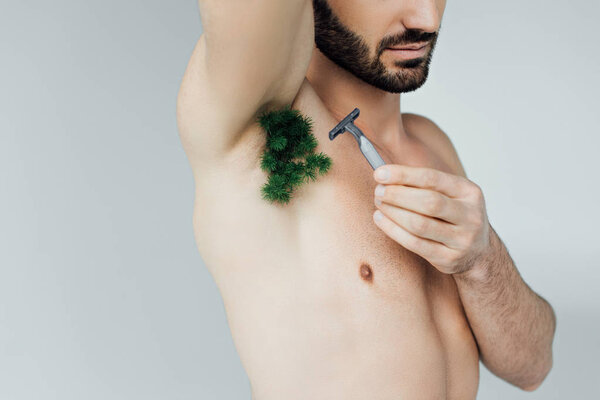 Cropped view of man shaving plant on armpit with razor isolated on grey