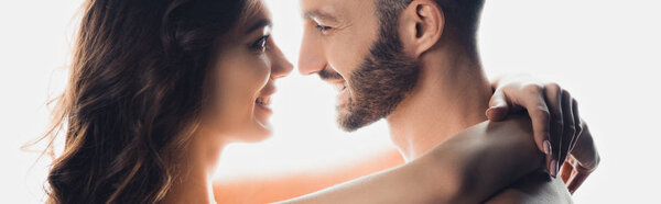 panoramic shot of nude smiling couple embracing isolated on white