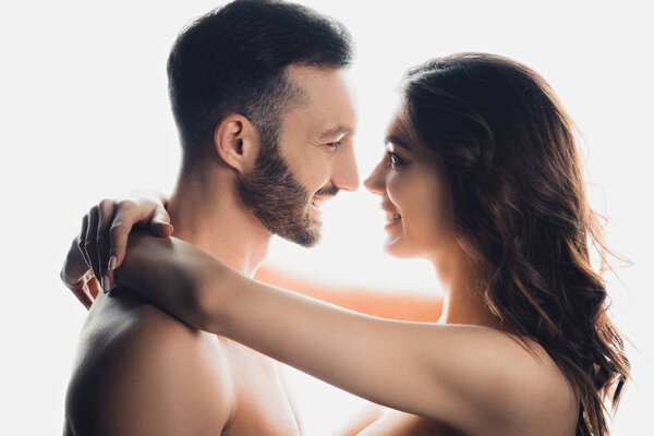 side view of nude smiling couple embracing isolated on white