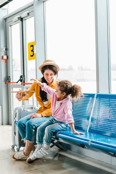 Cheerful African American Mother Daughter Sitting Airport Suitcase Wooden Plane — Stock Photo, Image