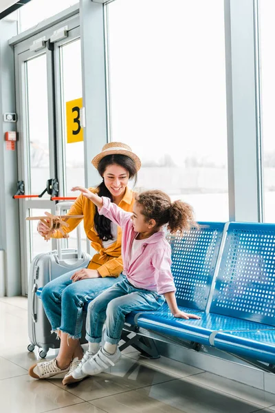 Alegre Africano Americano Madre Hija Sentado Aeropuerto Con Maleta Madera —  Fotos de Stock