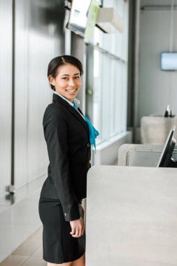 smiling african american airport staff in uniform standing at workplace  clipart