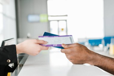 Havaalanı işçisi ve African American yolcu tutan pasaport ve hava bileti kırpılmış görünümü