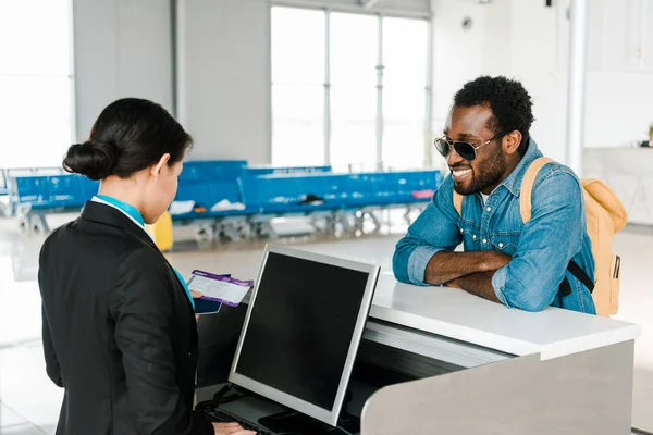 微笑的非裔美国机场工作人员检查机票在机场的机票控制 — 图库照片