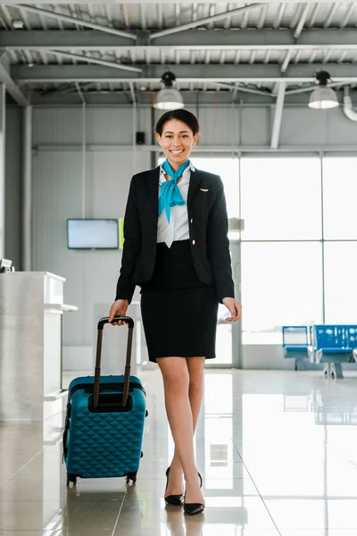 愉快的非洲裔美国空姐走与手提箱在机场 — 图库照片