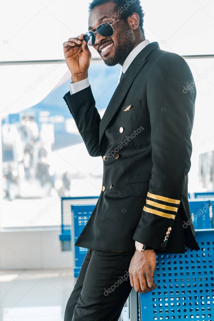 stylish smiling african american pilot in sunglasses in airport