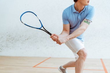 Spor merkezinde squash oynayan mavi polo gömlek sporcu kırpılmış görünümü