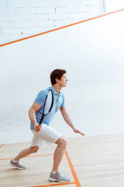 Spor merkezinde squash oynayan mavi polo gömlek konsantre sporcu