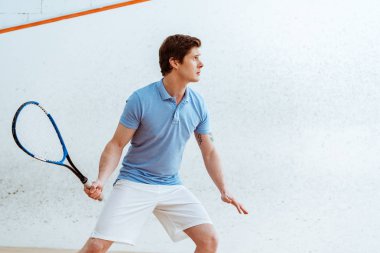 Spor merkezinde squash oynayan mavi polo gömlek konsantre sporcu