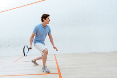 Spor merkezinde squash oynayan mavi polo gömlek konsantre sporcu