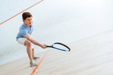 Dört duvarlı kortta squash oynayan mavi polo gömlek duygusal sporcu