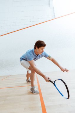 Dört duvarlı kortta squash oynayan mavi polo gömlek duygusal sporcu