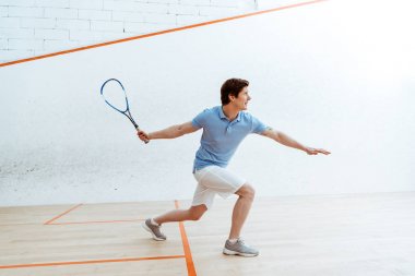 Dört duvarlı kortta squash oynayan mavi polo gömlek duygusal sporcu