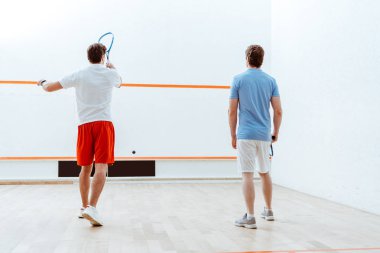 Dört duvarlı kortta squash oynayan iki sporcunun arka görünümü