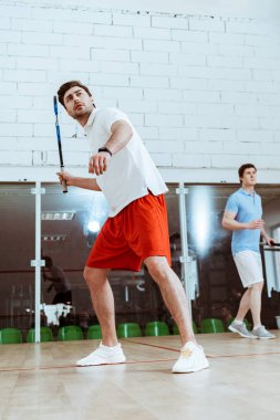 Dört duvarlı kortta squash oynayan iki sporcunun tam boy görünümü