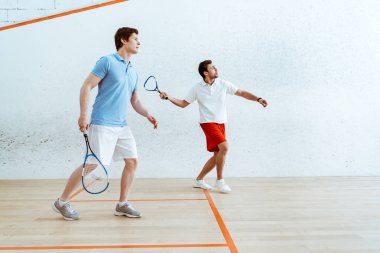 Dört duvarlı kortta squash oynayan iki sporcunun tam boy görünümü