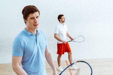 Mavi polo gömlek yakışıklı squash oyuncusu kameraya bakarak