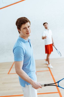 Mavi polo gömlek yakışıklı squash oyuncusu kameraya bakarak