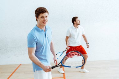 Mavi polo gömlek yakışıklı squash oyuncusu kameraya bakarak