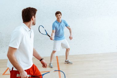 Raketleri ile Squash oyuncular dört duvarlı kortta birbirlerine bakıyor