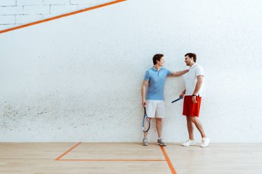 Arkadaşı omzuna el koyarak squash oyuncu tam uzunlukta görünümü