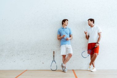 Dört duvarlı kortta konuşan squash oyuncularının tam boy görünümü