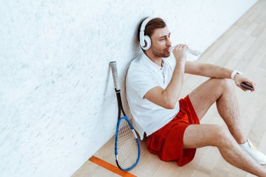Kulaklık ve içme suyunda müzik dinleyen squash çalar yüksek açı görünümü