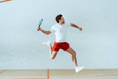 Dört duvarlı kortta squash oynarken polo gömlek atlama sporcu