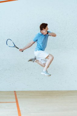 Dört duvarlı kortta squash oynarken polo gömlek atlama sporcu