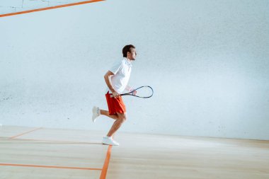 Squash oynarken raket çalışan sporcunun tam uzunlukta görünümü