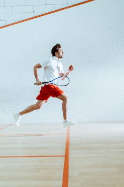 Squash oynarken raket çalışan sporcunun tam uzunlukta görünümü