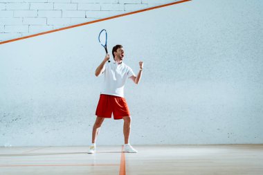 Evet jest gösteren raket ile mutlu squash oyuncu tam uzunlukta görünümü