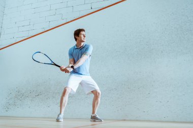 Squash oynayan mavi polo gömlek konsantre sporcu tam uzunlukta görünümü