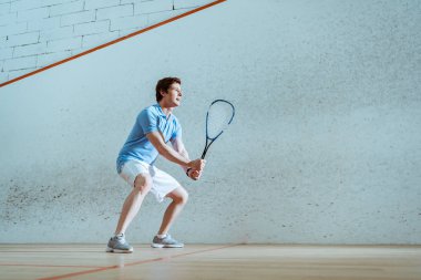 Squash oynayan mavi polo gömlek konsantre sporcu tam uzunlukta görünümü