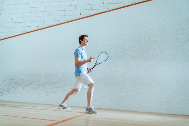 Gülümseyen squash oyuncusunun parmakla işaret tam uzunlukta görünümü