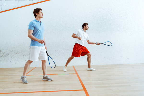Full length view of two sportsmen playing squash in four-walled court
