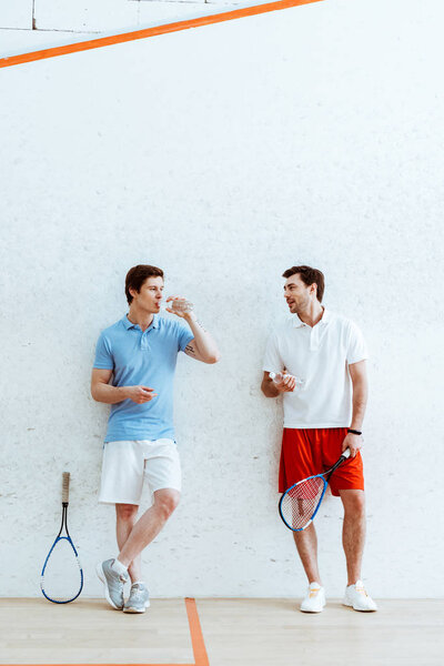 Full length view of squash players talking in drinking water