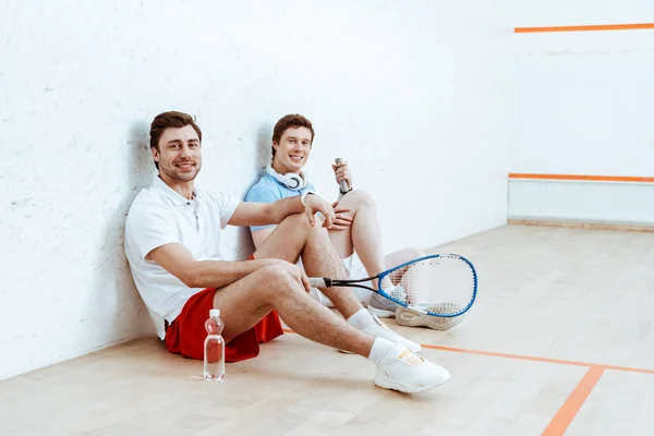 Dos Jugadores Squash Sonrientes Sentados Suelo Una Cancha Cuatro Paredes — Foto de Stock