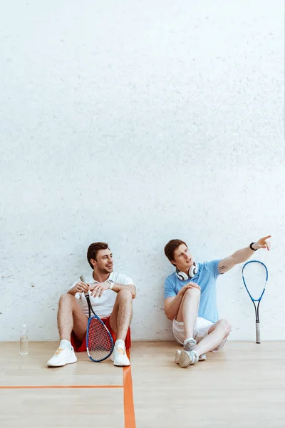 Squash Jugador Sentado Suelo Con Amigo Señalando Con Dedo —  Fotos de Stock