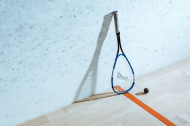 Squash racket and ball on wooden floor in four-walled court clipart