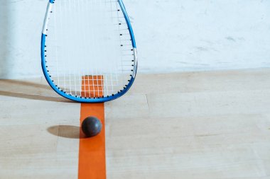 Squash racket and ball on wooden floor in four-walled court clipart