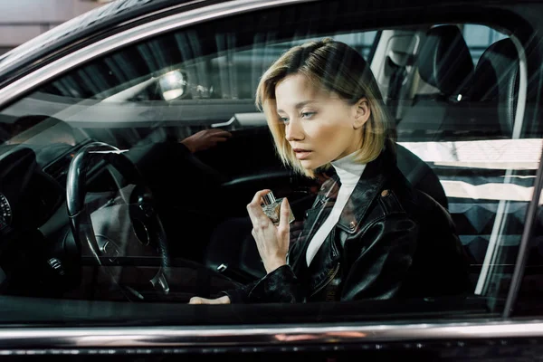 車の中で香水瓶を持つ魅力的なブロンドの女性 — ストック写真