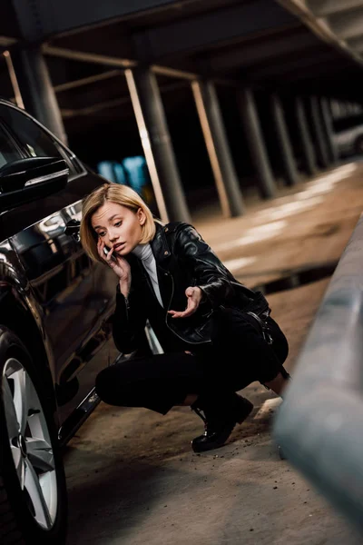 Järkyttynyt Blondi Tyttö Puhuu Älypuhelimella Elehtii Istuessaan Auton Lähellä — kuvapankkivalokuva