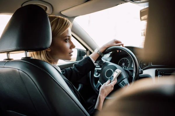 Atrakcyjna Blond Kobieta Siedzi Samochodzie Trzyma Smartfon — Zdjęcie stockowe