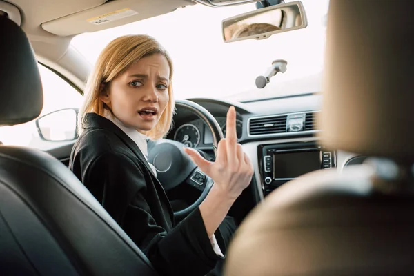 Stressé Fille Blonde Montrant Majeur Tandis Que Assis Dans Voiture — Photo